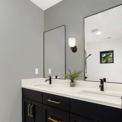 Bathroom interior with oil rubbed bronze wall sconce with frosted glass shade above vanity mirror, mounted up.