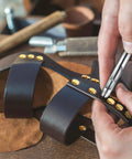 Close-up of a hand attaching 60 Pairs Solid Brass Chicago Screws For Belts And Jeans Including Heavy Duty Hole Punch Kit For Leather Straps And Clothing Repair on leather sandals.