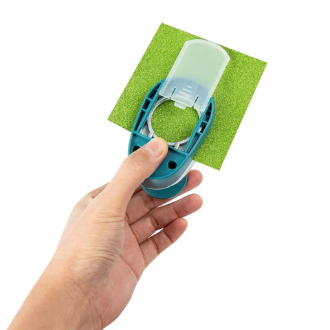 Hand holding 2-piece circle cutter set with 1.5 inch and 1 inch punches for paper crafts, showing clean round circle cut on green paper.