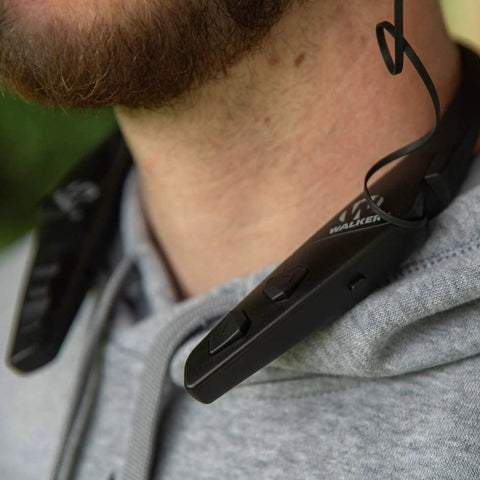 Close-up of person wearing Behind The Neck Bluetooth Hearing Enhancer For Hunters With Retractable Earbuds, rugged black design