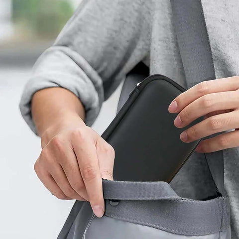 Person reaching for Legit Eva Hardshell Power Bank Case With Heavy Duty Zipper in a gray bag, showcasing its sleek design.