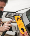 Professional Grade Paintless Dent Removal Kit featuring sturdy orange puller held by a person repairing a car panel.
