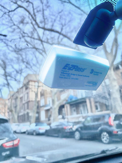 EZ Pass transponder mounted with Two Sets Of No Brainer Easy Peel And Stick Mounting Strips For EZ Pass IPass IZoom SunPass Transponders Quick On Windshield Or Dashboard Reclosable Dual Lock Tape For Your Car visible through car windshield.