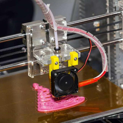 Side view of 3D printer extruder with pink PTFE tubing and PC4 push-fit fittings; yellow clamp blocks and cooling fan.