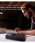 Heavy Duty 3 In 1 Stud Finder And Wall Scanner on table as user measures distance with pen, highlighting LCD display features.
