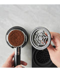 Espresso Knock Box And Pro Tamper Combo Fits Most Portafilters Heavy Duty Abs Build. Close-up of portafilter and calibrated tamper with ground coffee.