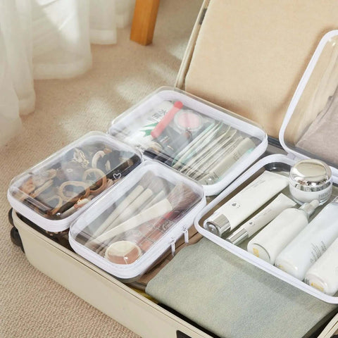 Hella Tough Four Piece Clear Hard Shell Case With Secure Zipper Closure organized with makeup brushes and cosmetics in suitcase.