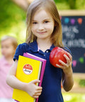 Child holding books and apple with Hello My Name Is Round Name Tag Stickers Set 315 Pcs In 9 Macaron Colors sticker visible