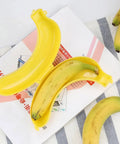 Reusable Banana Keeper Guard With Secure Snap Lid keeps bananas fresh inside yellow container on striped towel.