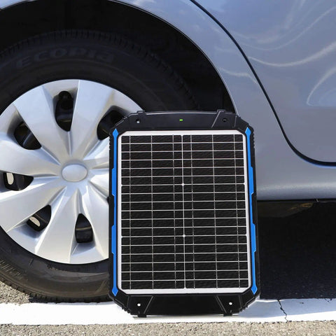 20W 12V Solar Battery Trickle Charger And Maintainer with Built In MPPT Controller next to car tire