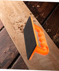 Safety Push Block for Table Saws and Router Tables Lightweight Portable Orange Woodworking Push Block for Workshops Safer Cuts and Precise Control All Day Performance with ABS handle and base on a wooden surface.