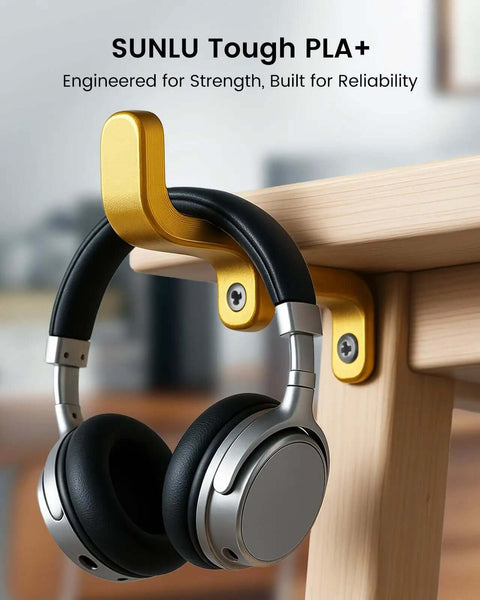 Silver headphones hanging on gold desk hook, mounted under a wooden desk.