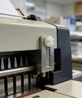 Close-up of a 50 Pack White 632 X 1 2 Slotted Switch Plate Screws Includes Tidy Latch Container on a machine.