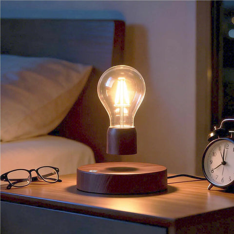 Floating LED Light Bulb Desk Lamp With Magnetic Levitation And Wireless Induction Power on wooden base next to bed and clock