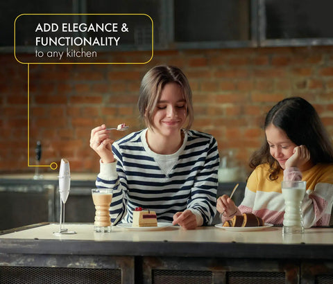 Handheld Milk Frother And Electric Whisk With 19000 RPM Power Includes Recipe Book And Stainless Steel Stand White And Gold Finish Perfect For Lattes Cappuccinos And More shown on a kitchen counter next to people enjoying desserts