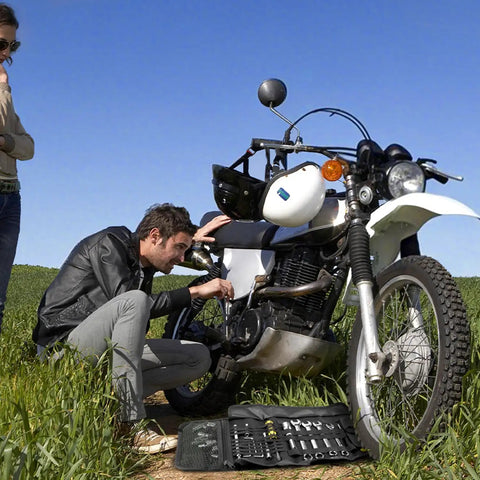 Man using Roll Up Ride Ready Motorcycle Tool Roll Bag Pouch And Wrench Organizer for bike repairs on a grassy path