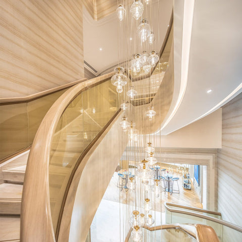 Elegant staircase with glass railing and hanging lights