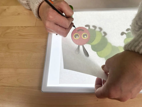 Portable LED Light Pad For Crafting And Quilting 10 By 13 Inch, showing tracing of cartoon caterpillar, bright illumination for crafts.