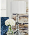 Big Glam Crystal Bead Table Lamp With Clear Glass Tubes And Shiny Chrome Finish displayed with a white hardback drum shade