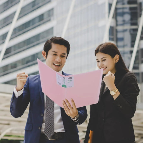 Two professionals excitedly reviewing a document in a pink 60 Pocket Portfolio Binder Organizer With Clear Sheet Protectors For 8.5 By 11