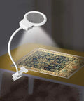 LED Magnifying Lamp For Diamond Painting Tools With 4X And 6X Magnifier illuminating a cross stitch project on a table.
