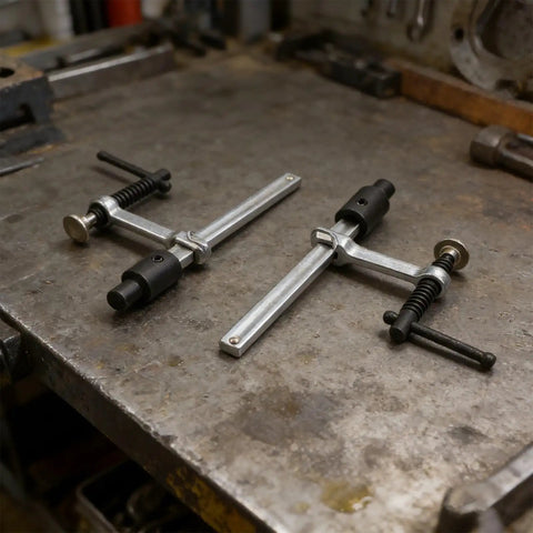 Two Pack Quick Action Bench Dog Clamps For 16mm Holes Hold Down Clips on workbench, silver black metal, ergonomic grip.