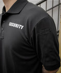 Mens Short Sleeve Security Polo Shirt Black with 'SECURITY' print, showing detail on collar and shoulder for patrol duty.