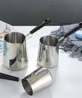 Three stainless steel Turkish coffee pots with pour spouts and black handles for milk chocolate butter and sauce heating