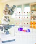 Festfends Metal Test Tube Drying Rack For Lab Use, Practical White Holder With 24 Slots next to a microscope on a lab table.