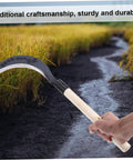 Hand holding Durable Manganese Steel Scythe Long Hand Hoe For Garden Weeding Heavy Duty Yard Work Tool with sharp edge in field
