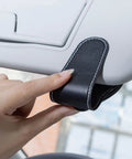Close-up of Porsche Sunglasses Holder Car Clip for Visor, showing one-hand operation with leather material in black.