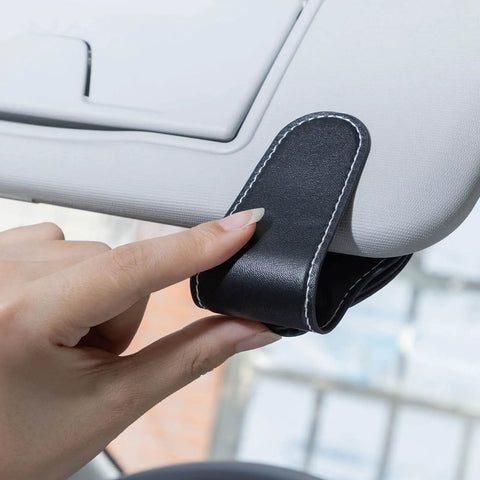 Close-up of Porsche Sunglasses Holder Car Clip for Visor, showing one-hand operation with leather material in black.