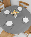 Round Vinyl Tablecloth With Elastic Edge And Flannel Backing, No-Slip No-Fuss 100 Percent Waterproof Fitted Cover For 36 To 44 Inch Tables, Wipeable Plastic Table Cloth For Picnic And Outdoor Use, Grey, shown on a dining table with plates and cutlery.