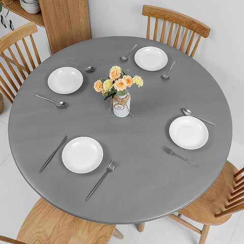 Round Vinyl Tablecloth With Elastic Edge And Flannel Backing, No-Slip No-Fuss 100 Percent Waterproof Fitted Cover For 36 To 44 Inch Tables, Wipeable Plastic Table Cloth For Picnic And Outdoor Use, Grey, shown on a dining table with plates and cutlery.