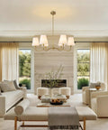 Smooth Operator 6 Light Brass Gold Chandelier With White Fabric Shades illuminating a bright dining area with modern decor.