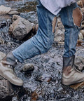 Person hiking through stream wearing Waterproof Rain Boot Covers For Men And Women, Reusable Foldable Overshoes, ankle high grey.
