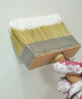 5.5 Inch Limewash Deck Brush With Wood Handle Large Paint Applicator for walls and fences in use by gloved hand