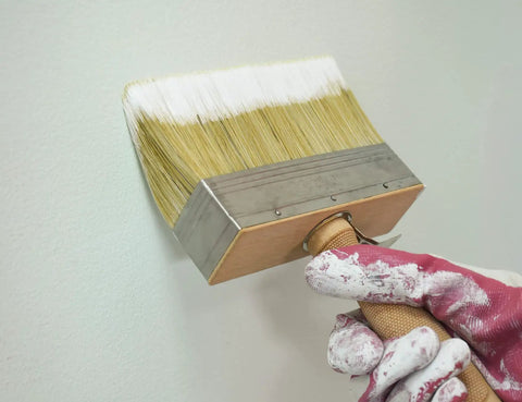 5.5 Inch Limewash Deck Brush With Wood Handle Large Paint Applicator for walls and fences in use by gloved hand