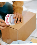 Person applying Fragile Warning Packing Tape Set With 5 Rolls, Heavy Duty Shipping Tape That Sticks Like Crazy, to box