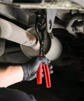 Under-vehicle view of ARES 14020 heavy-duty exhaust hanger removal pliers with red handles gripping a muffler hanger