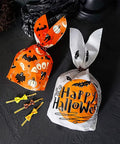 Halloween-themed treat bags with Gold Twist Ties For Treat Bags 750 Pcs Bulk Party Favor Bags Gift Bags Cookie Bags Cellophane Bags 3.94 Inch Length Easy To Twist And Seal Sturdy Durable Party Decor Great For Gifts And Party Treat Bags Easy To Store And Display on black surface.