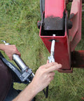 Person using Grease Gun Coupler XL Universal Fit With 3.5 Inch Extra Reach For Recessed Fittings on red machinery part