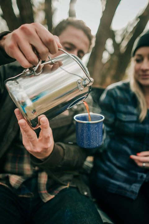 Person pouring coffee from Camper's Percolator Coffee Pot For Camping 9 Cup Aluminum Brew Coffee Pot into a blue mug
