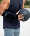 Person wearing a Red Light Therapy Wrist Wrap For Pain Relief And Carpal Tunnel Support while holding a basketball outdoors.