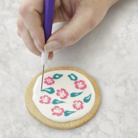 Close-up of cookie decorating using Top Shelf Cookie Decorating Tools Set Featuring Etching Wand Triple Comb And Flexible Silicone Scraper.