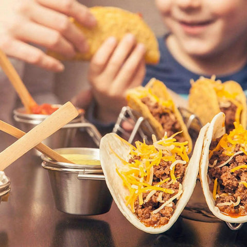 Stainless Steel 3 Grid Taco Holder With V Shaped Slots And No Spill Sauce Cups displayed with tacos and sauce in a party setting.
