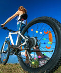 Colorful Bike Spoke Beads Kit For Kids on a mountain bike wheel with assorted shapes under blue sky