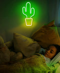A child sleeping under a green neon cactus light, wall decor for a cozy bedroom atmosphere.