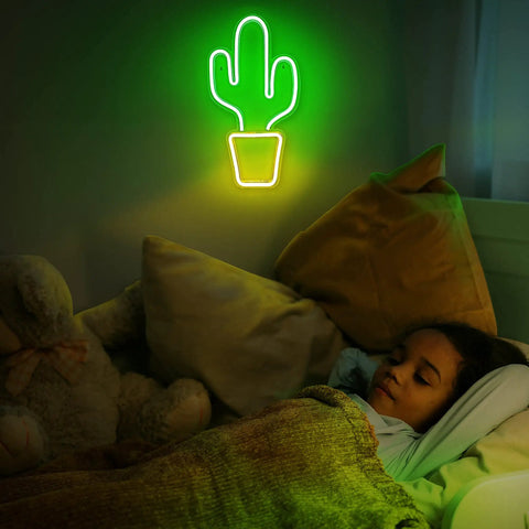 A child sleeping under a green neon cactus light, wall decor for a cozy bedroom atmosphere.
