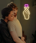 Finger Heart Neon Sign In Pink And Warm White For Bedroom And Game Room LED Light Hand Gesture Decor For K Drama And K Pop Fans Wall Decor Gift For Fans Vibe, with couple enjoying ambiance